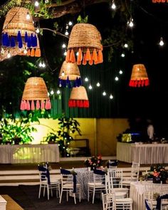 several lights hanging from the ceiling above tables and chairs with white tablecloths on them