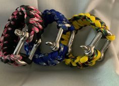 three different colored bracelets with metal clasps on white fabric background, closeup