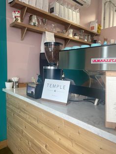 a coffee maker sitting on top of a counter next to a sign that says temple