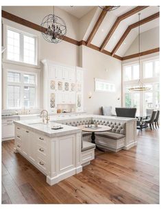 a large open concept kitchen with white cabinets and wood flooring is pictured in this image