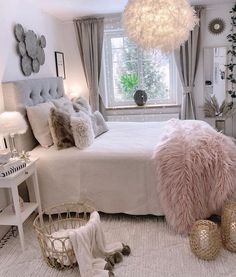 a bedroom decorated in white and grey with lots of pillows on the bed, lights hanging from the ceiling