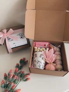 an open box on a table next to some pink flowers and other items in it