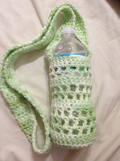 a crocheted water bottle bag sitting on top of a bed