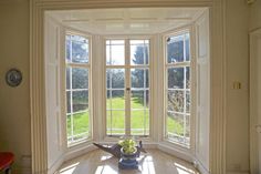 an empty room with three large windows and a potted plant