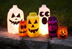 lighted pumpkins and jack - o'- lantern jars sitting on a rock