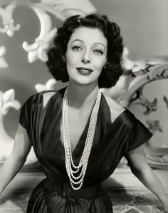 an old black and white photo of a woman with pearls on her necklace, posing for the camera