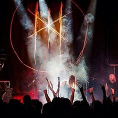 the band performs on stage with their hands in the air