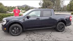 a man standing on the back of a truck in a parking lot with his arms out