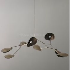 a modern chandelier with four lights hanging from it's sides and leaves on the bottom