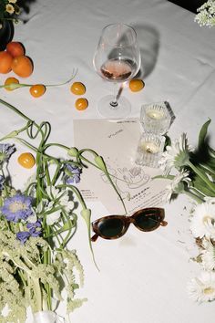 the table is covered with flowers, oranges and wine glasses on top of it