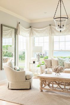 a living room filled with furniture and windows next to a window covered in white curtains