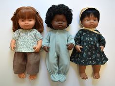 three dolls are standing next to each other on the wall, one is wearing a blue dress