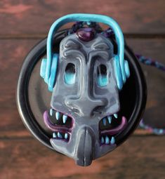 a close up of a metal object on a wooden surface with beads and chains around it