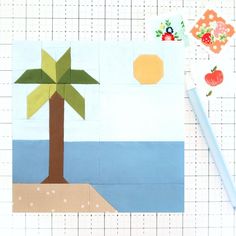 a piece of paper cut out to look like a palm tree and an apple on the beach