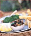 a white plate topped with food next to lemon wedges and green leafy vegetables