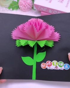 someone is holding up a flower made out of paper