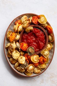 a plate filled with different types of food on top of a white tablecloth next to a wooden spoon