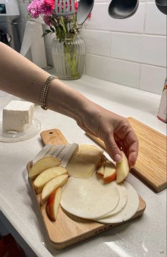 a person cutting apples on top of a wooden cutting board