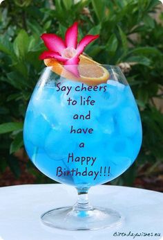 a blue drink with a flower in it and the words say cheers to life and have a happy birthday