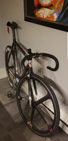 a bicycle is propped up against the wall in front of a painting on the wall