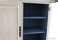 an open white cupboard with blue shelves in it