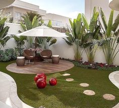 an outdoor area with grass, rocks and red balls on the ground in front of a white building