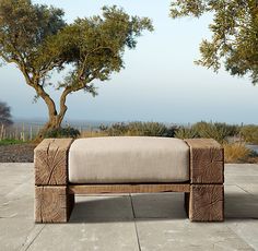 a bench sitting on top of a cement floor next to trees and bushes in the background