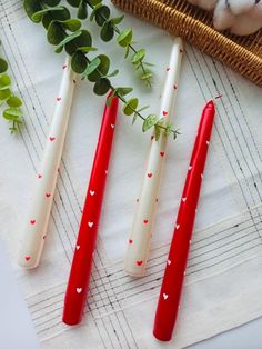 three red and white toothbrushes sitting on top of a table next to green leaves