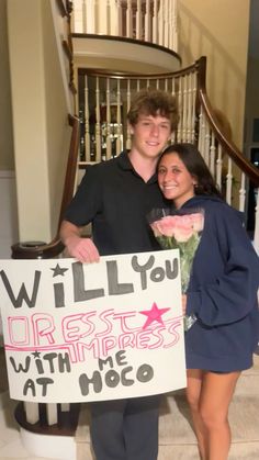 a man and woman standing next to each other holding a sign