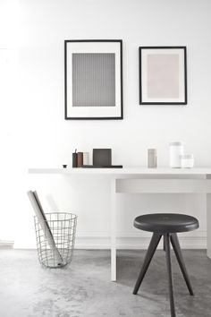 two framed pictures hang on the wall above a white table