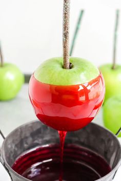 an apple is being dipped with red liquid