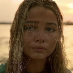 a close up of a person with long hair and water in the backgroud