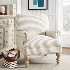 a striped chair sitting in front of a window next to a dresser with books on it