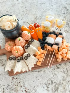 an assortment of halloween treats on a cutting board with marshmallows and candies