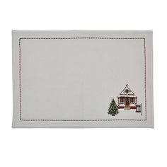 a white placemat with a house and christmas tree on it, in front of a white background