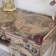 an old world map covered suitcase sitting on top of a table next to a clock