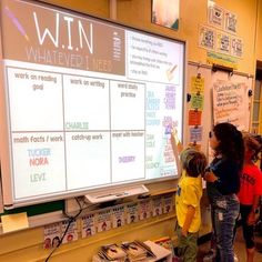 children are standing in front of a large screen