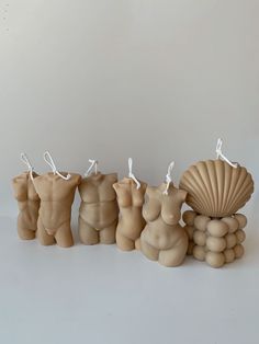 three clay figurines are standing next to each other, one is holding a shell