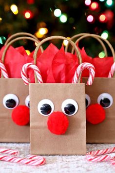 two paper bags decorated with candy canes and reindeer noses are sitting in front of a christmas tree