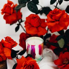 a candle and some red roses on a table