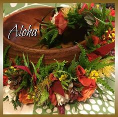 a wooden bowl filled with lots of flowers and greenery on top of a table