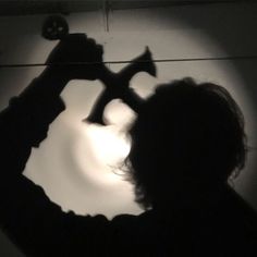 a man is holding a hammer in front of a light that reflects on the wall