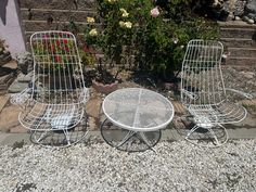 two chairs and a table sitting on gravel