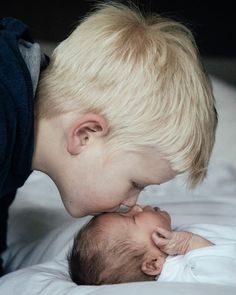 a young boy is kissing his newborn baby