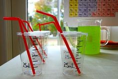 two measuring cups with red straws are sitting on a table