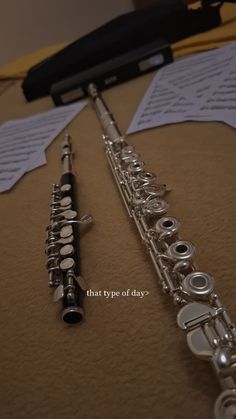 two silver flutes sitting next to each other on top of a table with music sheets