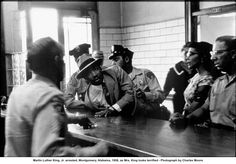 men in uniform sitting at a bar with one man wearing a fedora and the other standing