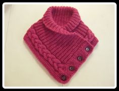 a pink knitted sweater with buttons on the front and back, sitting on a white surface