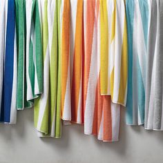 colorful towels hanging on a clothes line in front of a white wall with multiple colors