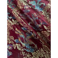 a close up view of a red and gold fabric with dragon designs on it's side